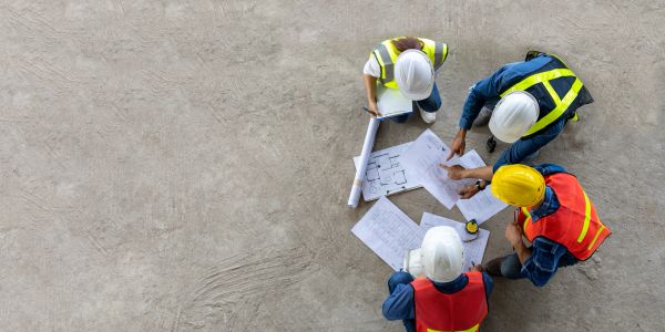 Construction workers reviewing blueprints aerial overhead